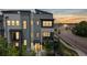 Modern townhome boasts a multi-tone color scheme, inviting red door, and sunset view at 6799 Navajo St, Denver, CO 80221