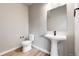 Modern powder room boasts a pedestal sink, wood-look flooring, and a sleek toilet at 6799 Navajo St, Denver, CO 80221