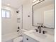 Bright bathroom features a shower over tub, modern black hardware, and a bright window at 6488 E 63Rd Pl, Commerce City, CO 80022
