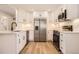Bright kitchen boasts stainless steel appliances, white cabinets, stone countertops and hardwood floors at 6488 E 63Rd Pl, Commerce City, CO 80022