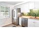 Well-organized kitchen with stainless steel appliances, white cabinets, and striking green backsplash at 1749 Havana St, Aurora, CO 80010