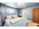 Serene bedroom with blue walls, floral curtains, wood floors, and ample natural light at 2360 Estes St, Lakewood, CO 80215