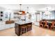 Well-lit kitchen with a center island, seating, copper sink and range hood and open shelving at 2360 Estes St, Lakewood, CO 80215