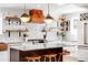 Bright kitchen featuring a center island with seating, a copper range hood, and open shelving at 2360 Estes St, Lakewood, CO 80215