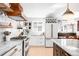 Well-lit kitchen boasts white cabinets, marble countertops, copper hardware, and a stainless steel refrigerator at 2360 Estes St, Lakewood, CO 80215