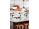 Bright kitchen featuring white cabinets, marble countertops, copper range hood, and stylish pendant lighting at 2360 Estes St, Lakewood, CO 80215