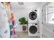 Stacked washer and dryer on tiled floor with bright lighting and colorful quilt at 2360 Estes St, Lakewood, CO 80215