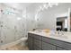 Bathroom featuring a double vanity, a large mirror, and a walk-in shower with decorative tile at 12273 Karls Ln, Northglenn, CO 80241