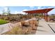 Community space with picnic tables beneath a red pergola and a landscaped garden at 12273 Karls Ln, Northglenn, CO 80241