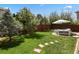 Green backyard featuring mature trees, a manicured lawn, and a stone pathway at 16164 E Hinsdale Ave, Aurora, CO 80016