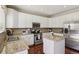 Well-lit kitchen featuring white cabinetry, granite countertops, and modern appliances at 16164 E Hinsdale Ave, Aurora, CO 80016