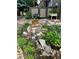 A charming rock-bordered flower garden with blossoming plants and a tree stump centerpiece at 10732 W Florida Ave # B, Lakewood, CO 80232