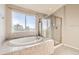 Bathroom features a soaking tub, glass shower, neutral tile, and natural light from the window at 14652 Beeler St, Brighton, CO 80602