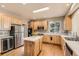 Bright kitchen boasts wooden cabinets, stainless steel appliances, a center island, and hardwood floors at 14652 Beeler St, Brighton, CO 80602