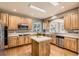 Well-lit kitchen featuring wooden cabinets, stainless steel appliances, a center island, and hardwood floors at 14652 Beeler St, Brighton, CO 80602