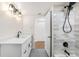 Modern bathroom featuring white vanity, grey tile floors, and walk-in shower with black fixtures at 3315 S Monaco St # B, Denver, CO 80222