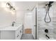 Modern bathroom with white vanity, black fixtures, tub with tiled walls, and gray tile floors at 3315 S Monaco St # B, Denver, CO 80222