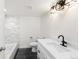 Modern bathroom with white vanity, black fixtures, tub with tiled walls, and dark tile floors at 3315 S Monaco St # B, Denver, CO 80222