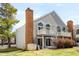 Rear exterior view of townhome with brick chimney, balcony, lawn and mature landscaping at 3315 S Monaco St # B, Denver, CO 80222