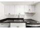 Bright kitchen with white cabinets, stainless steel appliances, and black countertops at 3315 S Monaco St # B, Denver, CO 80222