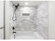 Updated shower featuring white and gray tiling with a recessed shelf and black hardware at 3315 S Monaco St # B, Denver, CO 80222