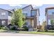 Contemporary two-story home featuring gray siding, brick accents, a yellow front door and a landscaped yard at 6682 Osage St, Denver, CO 80221