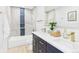 Well-lit bathroom featuring double sinks, navy blue vanity, and a tub with a shower at 3150 S Pennsylvania Street, Englewood, CO 80113