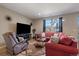 Cozy living room with a comfortable red sofa, a recliner, and plenty of natural light at 14921 W 70Th Ave, Arvada, CO 80007