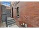 Brick exterior with a gray wooden fence and a small set of stairs leading to the gate and backyard at 2560 Champa St, Denver, CO 80205