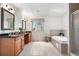 Bright bathroom featuring tile flooring, wooden cabinets, double sinks, a large tub, and glass door shower at 6275 Ponderosa Way, Parker, CO 80134