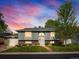 Charming gray two-story home with brick accents, lush lawn, and mature tree at sunset at 6869 Quay St, Arvada, CO 80003
