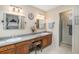 Well-lit bathroom featuring double sinks, a vanity, and a separate shower area at 8314 S Everett Way # B, Littleton, CO 80128