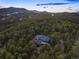 Aerial view of home with dark roof nestled amongst dense forest and mountains in the background at 28890 Pinewood Vista Dr, Evergreen, CO 80439
