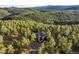 Aerial shot of home with dark roof surrounded by dense green forest and trees at 28890 Pinewood Vista Dr, Evergreen, CO 80439