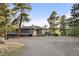 Exterior of home with circle driveway surrounded by a forest of tall trees at 28890 Pinewood Vista Dr, Evergreen, CO 80439