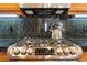Close-up of stainless steel range with black countertop and wood cabinets above at 40 Madison St # 203, Denver, CO 80206