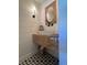 Modern bathroom with unique wood vanity, geometric tile floor, and stylish wall sconce at 8503 E Jamison Ave, Centennial, CO 80112