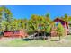 Rustic red home and outbuilding situated among tall trees, offering a serene and secluded setting at 548 Coughlin Meadows Rd, Boulder, CO 80302
