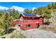 Red two-story home with solar panels and a detached outbuilding in a serene wooded setting at 548 Coughlin Meadows Rd, Boulder, CO 80302