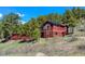 Charming red two-story home with lots of windows and solar panels nestled among trees at 548 Coughlin Meadows Rd, Boulder, CO 80302