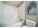 Close up of a bathtub with a tiled shower surround, toilet, and artwork in the bathroom at 9911 E Idaho Cir # 202, Denver, CO 80247