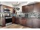 Modern kitchen with dark cabinets, stainless steel appliances, and stylish backsplash and hanging pot rack at 4620 Blackhawk Way, Denver, CO 80239
