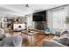 Open living room with brick fireplace, TV, and view into dining and kitchen area at 4620 Blackhawk Way, Denver, CO 80239