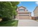 Two-story home featuring a two-car garage, brick accents, and a well-manicured lawn at 2446 S Gibralter Way, Aurora, CO 80013