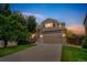 Two-story home featuring a two-car garage, brick accents, and a well-manicured lawn during twilight at 2446 S Gibralter Way, Aurora, CO 80013