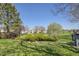 Lush backyard with mature trees and manicured lawn, featuring a deck overlooking a golf course at 8468 Chase Dr, Arvada, CO 80003