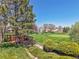 Backyard area features a small deck, manicured lawn, mature trees, and golf course views at 8468 Chase Dr, Arvada, CO 80003