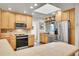 Well-lit kitchen featuring stainless steel appliances, tile countertops, a skylight and warm wooden cabinetry at 8468 Chase Dr, Arvada, CO 80003