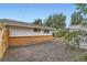A gravel-covered area with a building featuring brick accents and white siding, offering a low-maintenance backyard design at 5563 Newland Way, Arvada, CO 80002