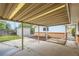 Covered carport area with mature trees, storage and yard at 5563 Newland Way, Arvada, CO 80002